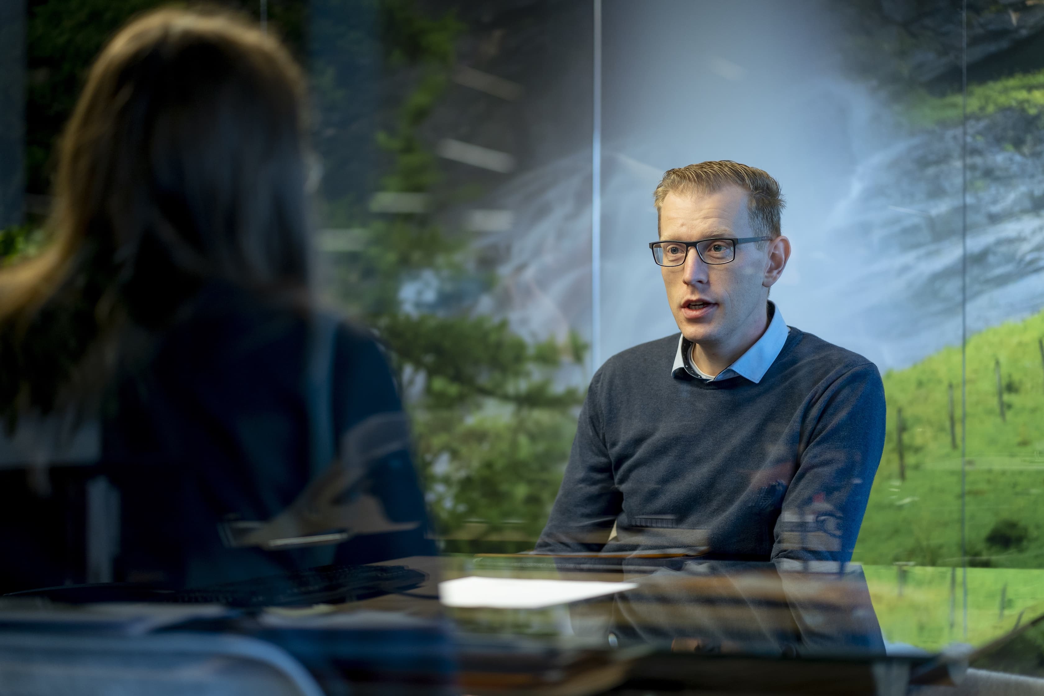 Man met bril in meeting met vrouw